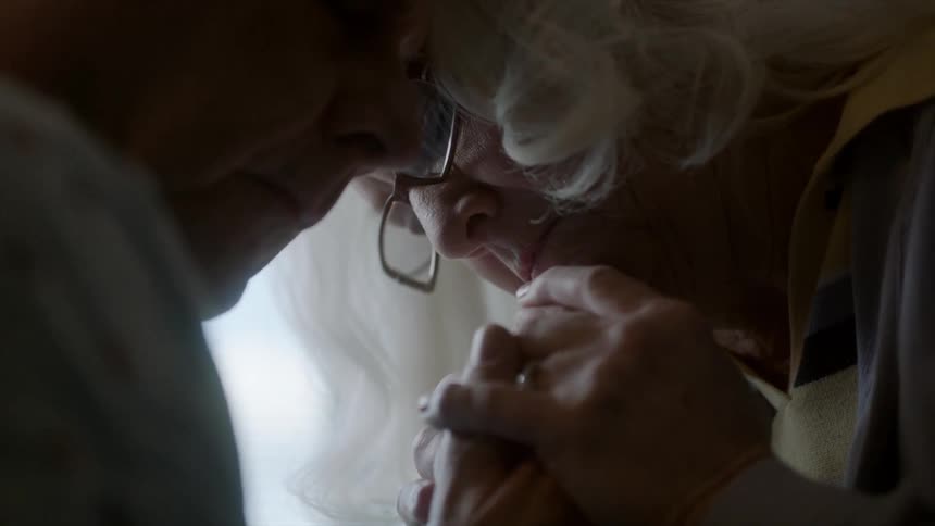 A man and woman hold hands and lean together