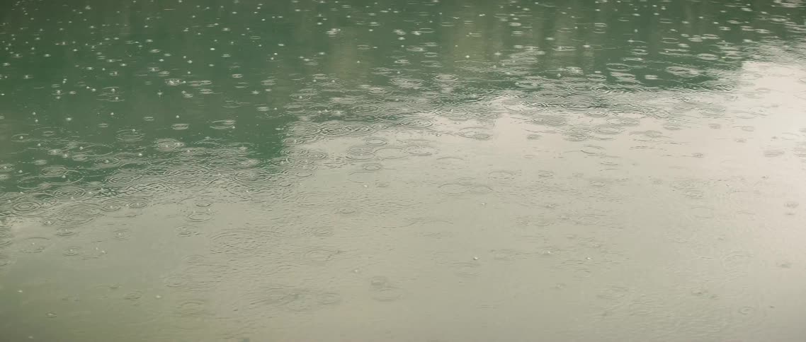 The rain pours slowly into the lake