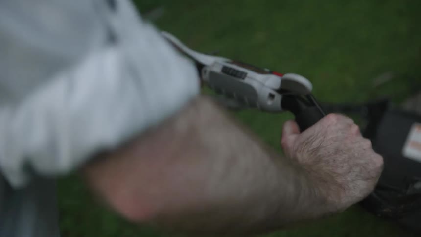 A man pushes a lawnmower in the lawn