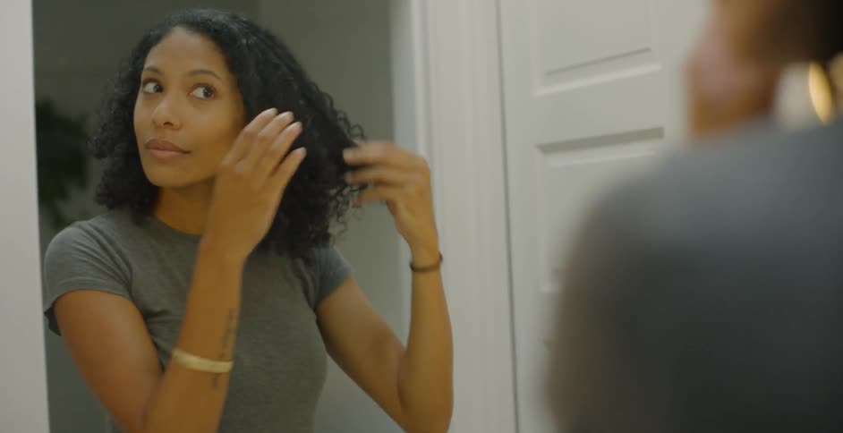 Woman fixes her hair in front of the bathroom mirror