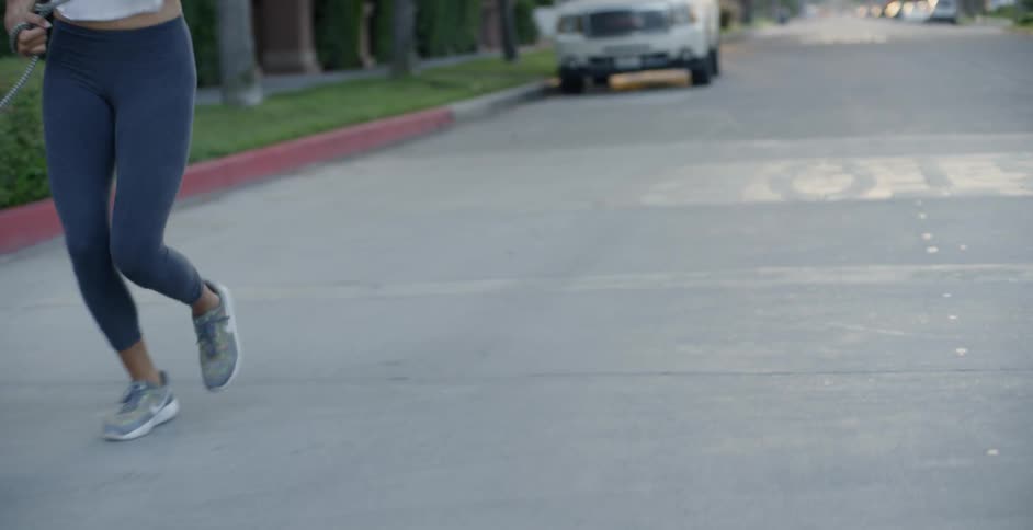 A woman and dog jog on a neighborhood street