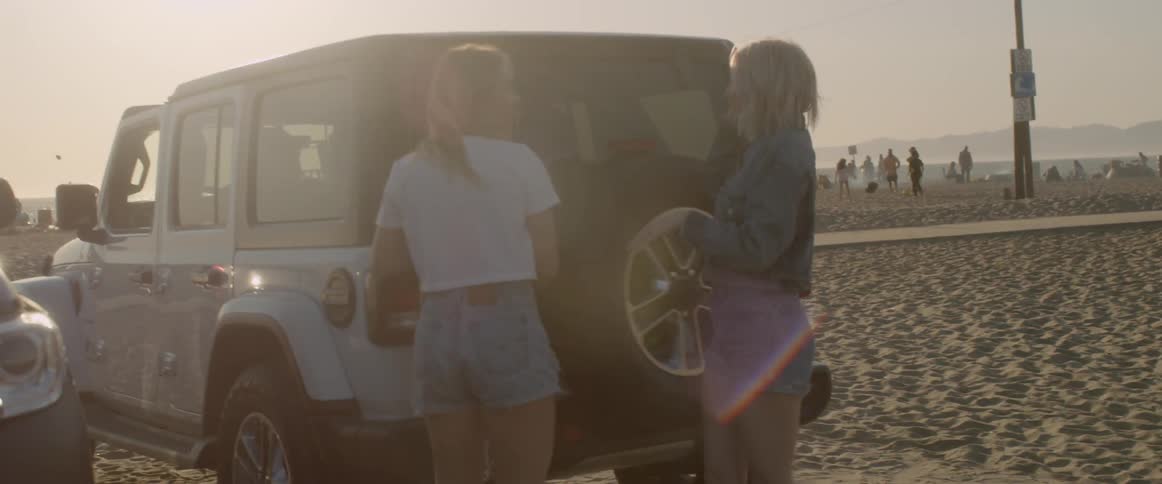The women open the vehicle to remove items and head to the beach