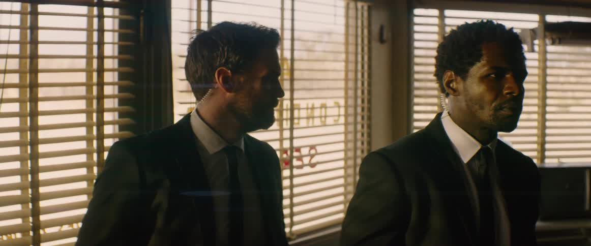 Two men in suits look at each other and nod