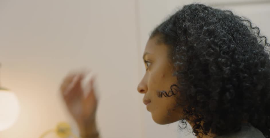 The woman brushes her hair back and adjusts in the mirror