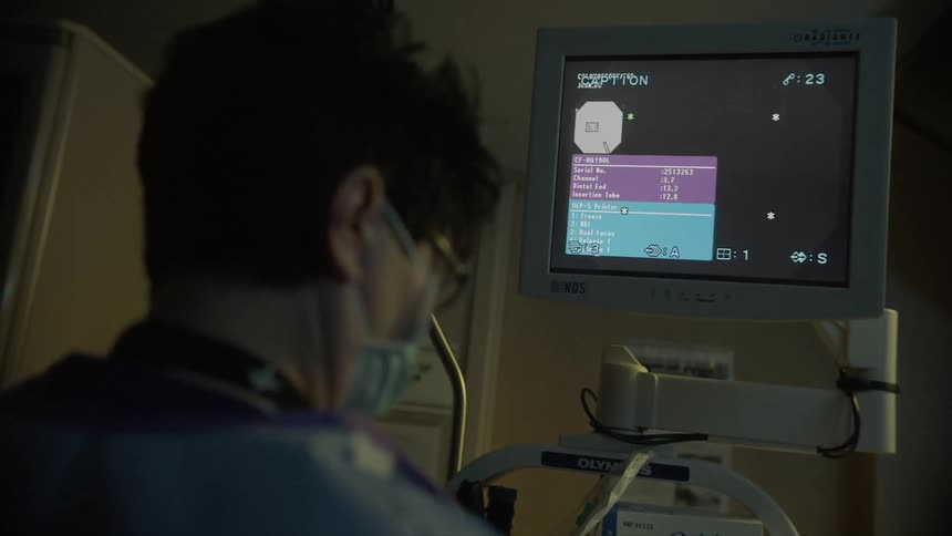 Woman wearing surgical mask looks at a medical monitor