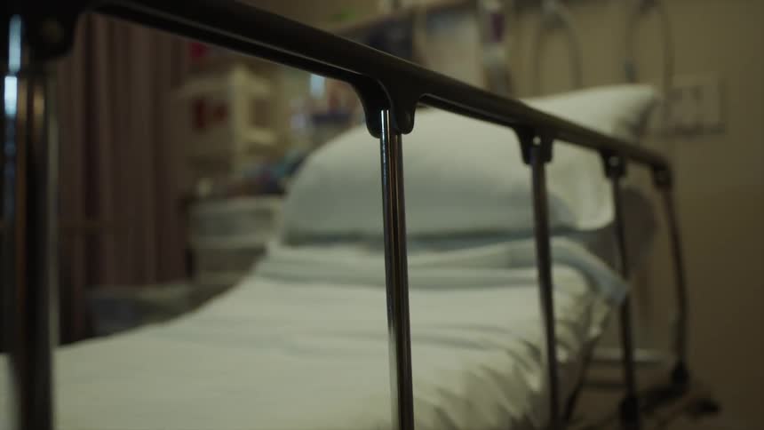 An empty hospital bed with the railing up