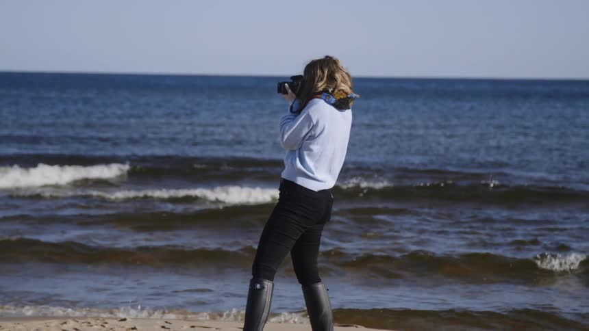The woman takes photos standing in the water