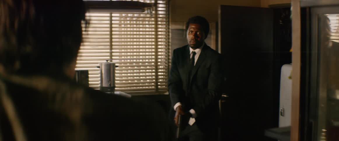 Man stomps into a room and points a gun at someone