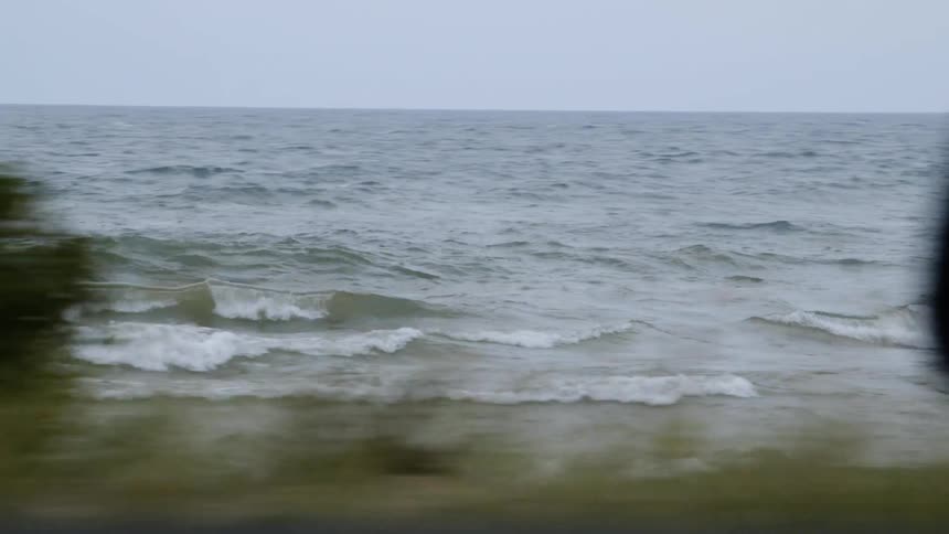 The vehicle passes the beach with rough waves