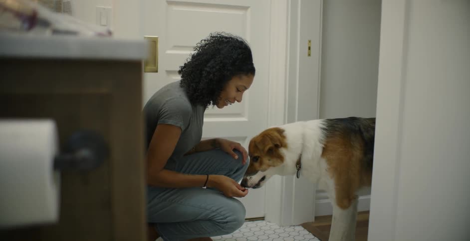 The woman feeds the dog a treat in the doorway