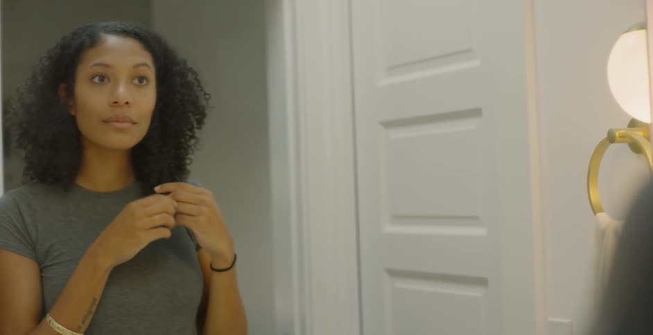 The woman fixes her hair in the mirror