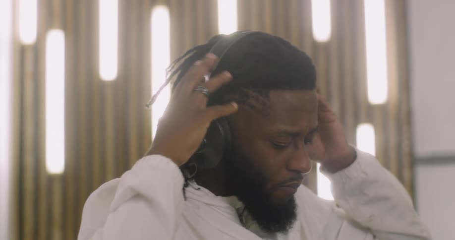 Man in a white shirt puts on headphones