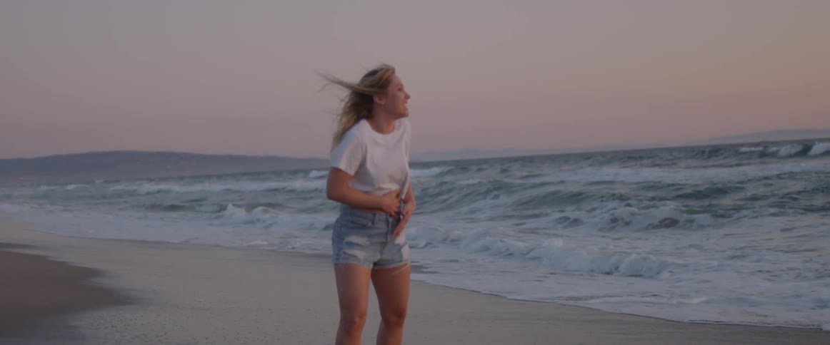 Two women run together and laugh on the beach