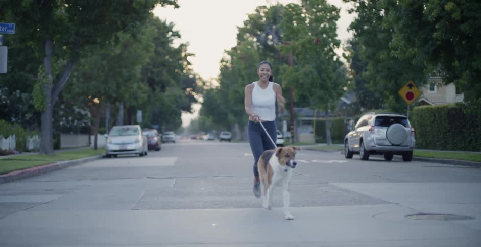 The woman runs behind her dog in the street