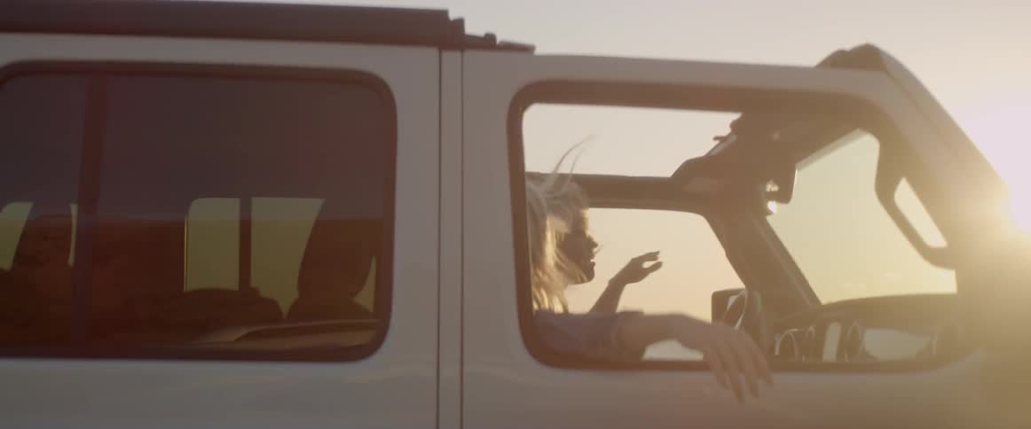 Two women ride in a vehicle with the windows down at sunset