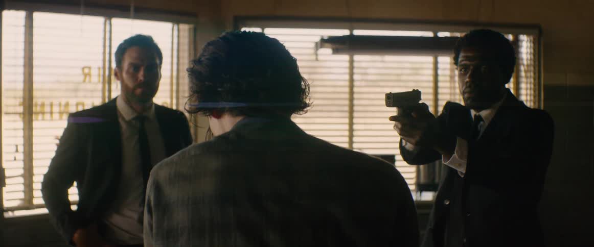 The man is pointing a gun at a store clerk