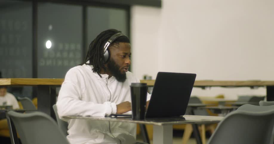 Man wearing headphones works on a laptop while sitting at a table