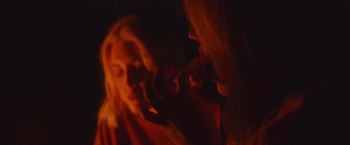 The two women eat treats by the campfire at night