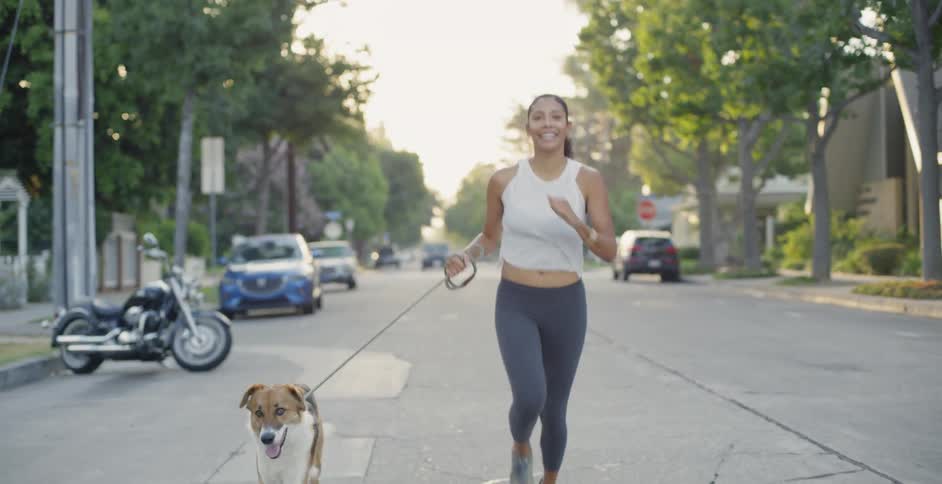 Woman runs with her dog on a city street
