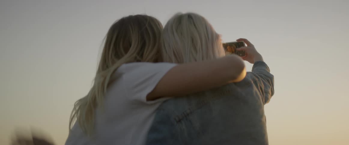 Two women pose for a picture that one woman takes with her camera