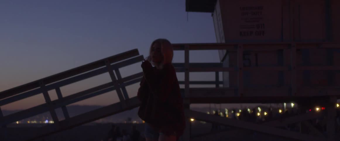 The woman stands in front of the lifeguard stand at dawn