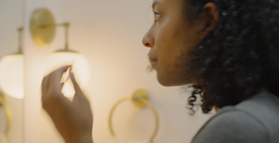 Woman fixes her hair and brushes on makeup