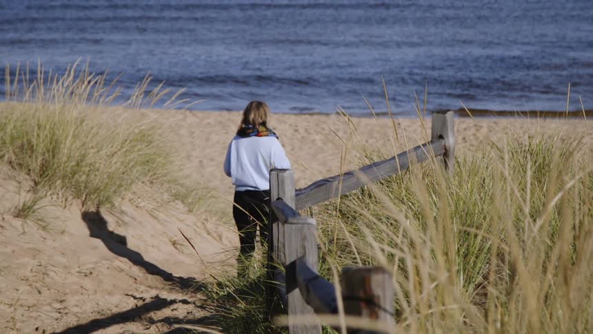 The woman walks towards the water on the beach