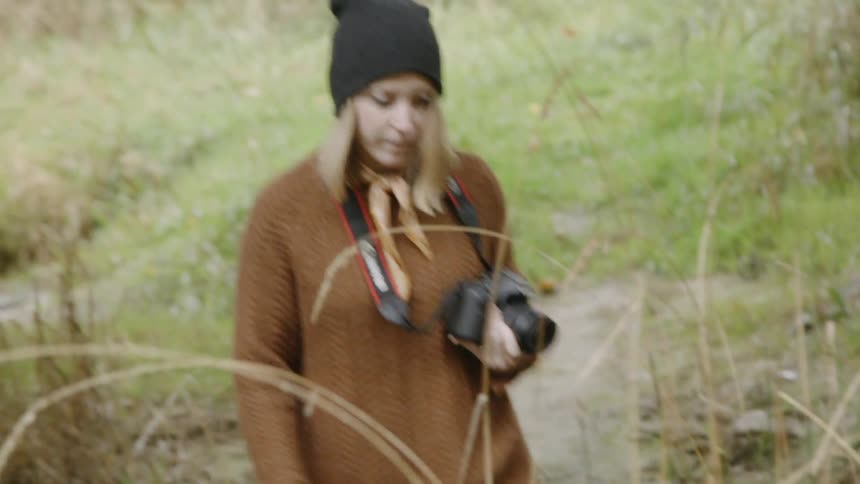 The woman carries her camera in the woods
