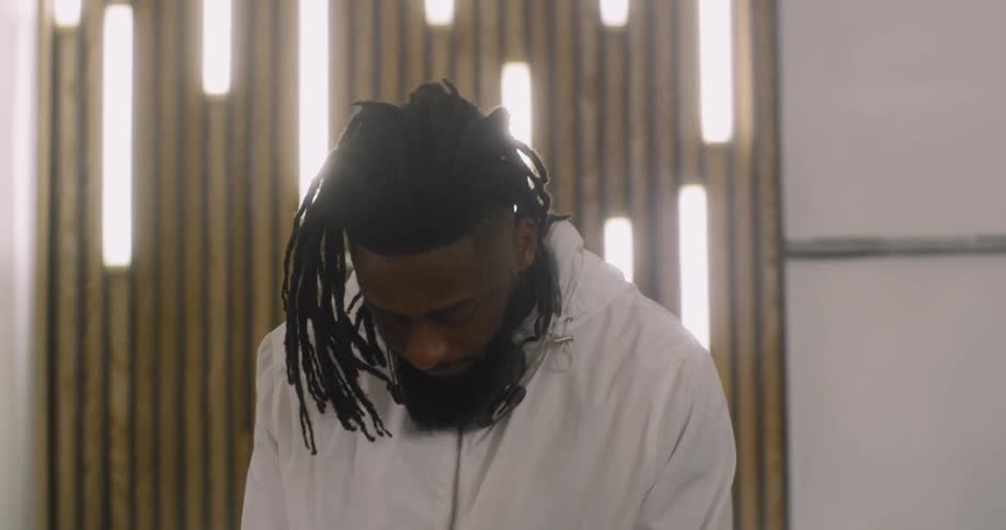 The man has headphones around his neck in the room