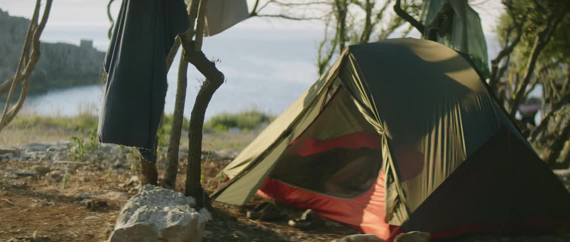 The wind blows the tent near the water