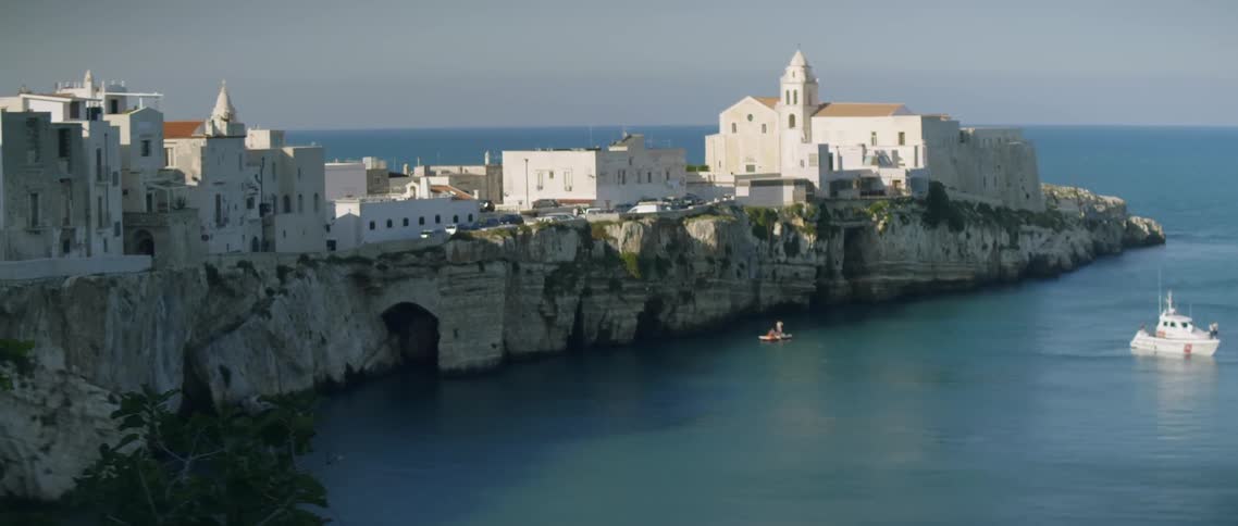 Sun shines down on white buildings next to the ocean