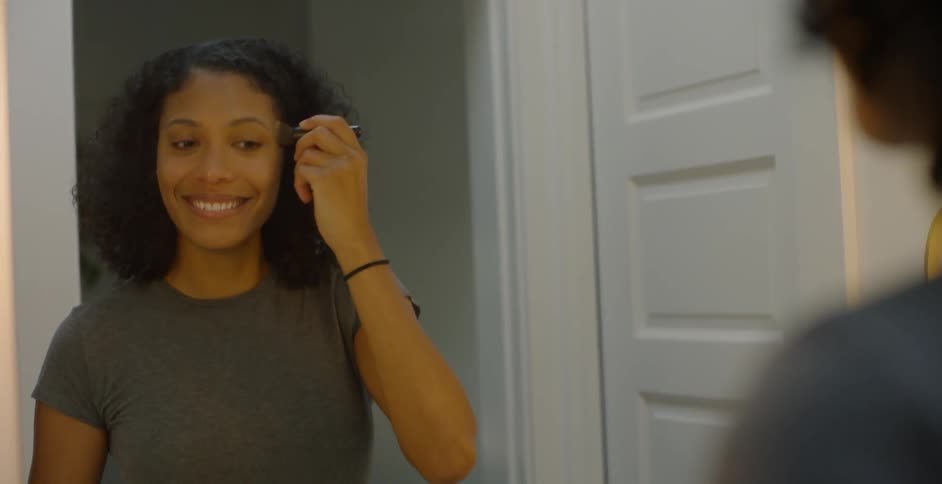 The woman is using a brush to apply makeup