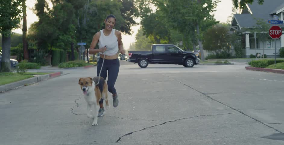 Woman jogs down the middle of the road with her dog