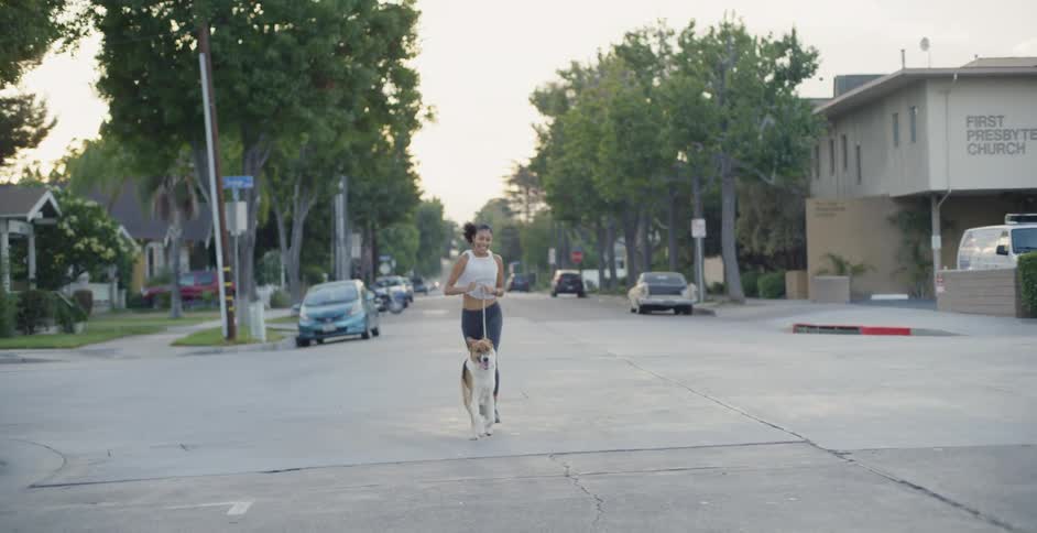 The woman runs in the street with her dog running by her side
