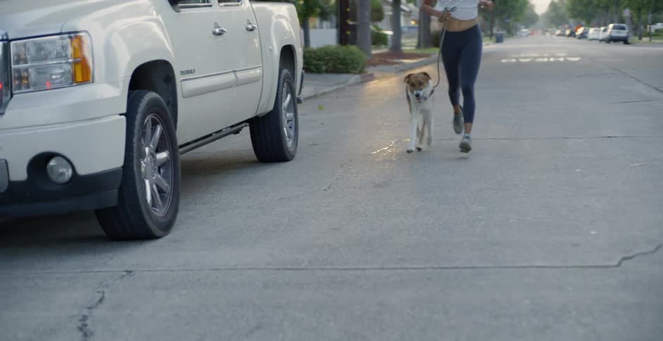 The woman jogs by the vehicles on the town street