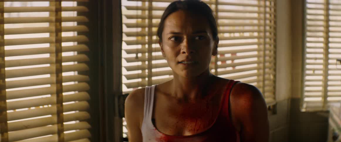 The woman stands by the blinds of the window