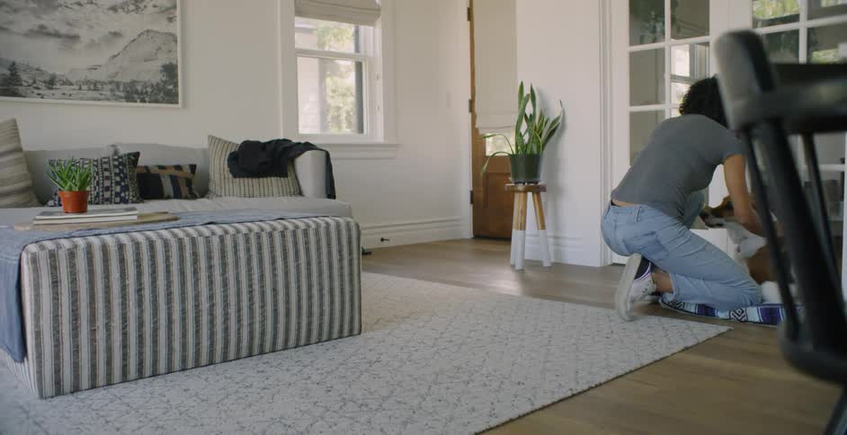Woman kneels in a living room petting a dog