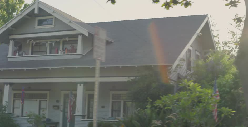 The sun shines behind houses on a neighborhood street