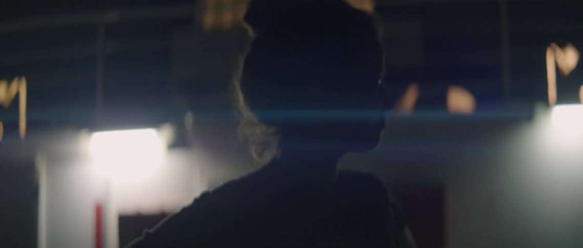 Woman stands outside of a lit building at night