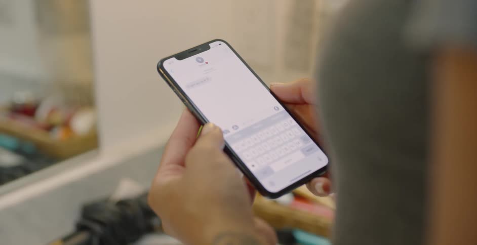 The woman operates her phone in front of the mirror