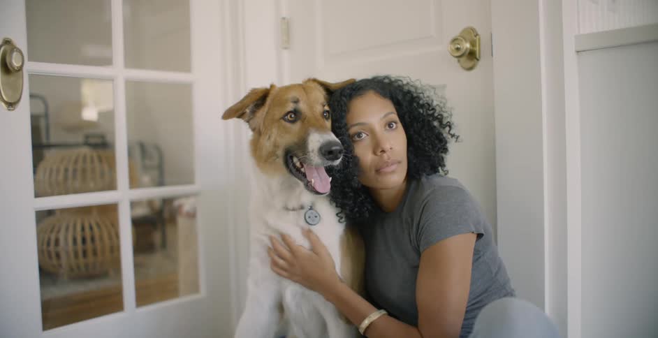 The woman leans against her dog petting him