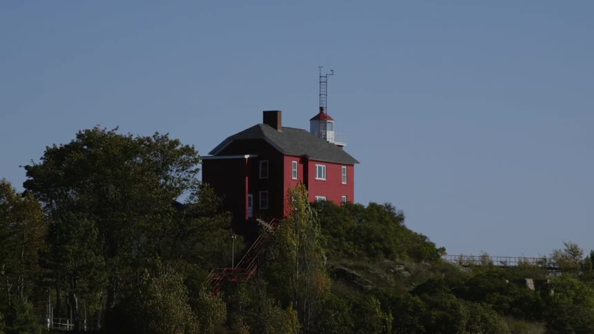 The red house is on top of the green hill