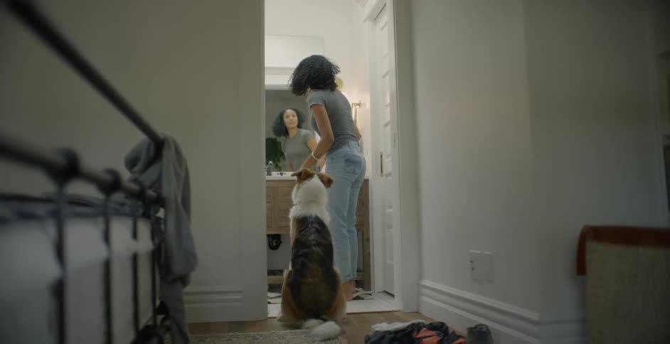 The woman pets her dog waiting patiently in the doorway