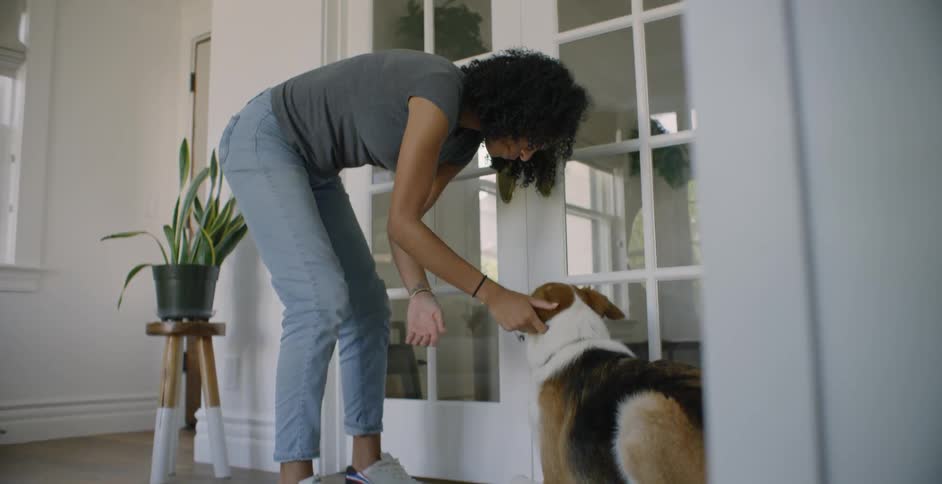 The woman leans down to pet her dog