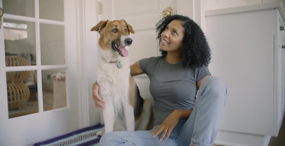 The woman sits patting her dog next to her
