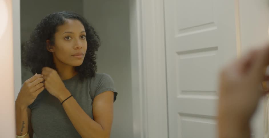 The woman adjusts her hair in the mirror