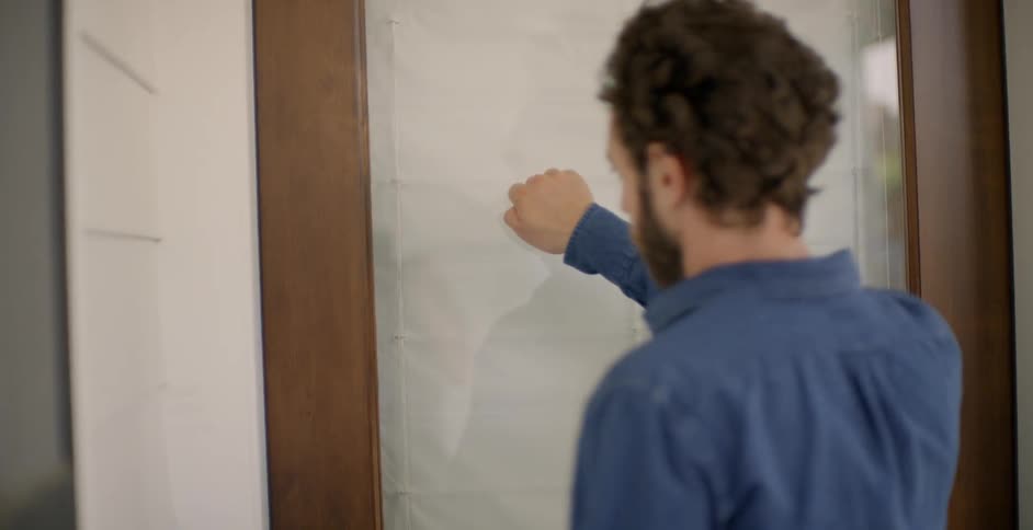 The man approaches the door and knocks on the glass