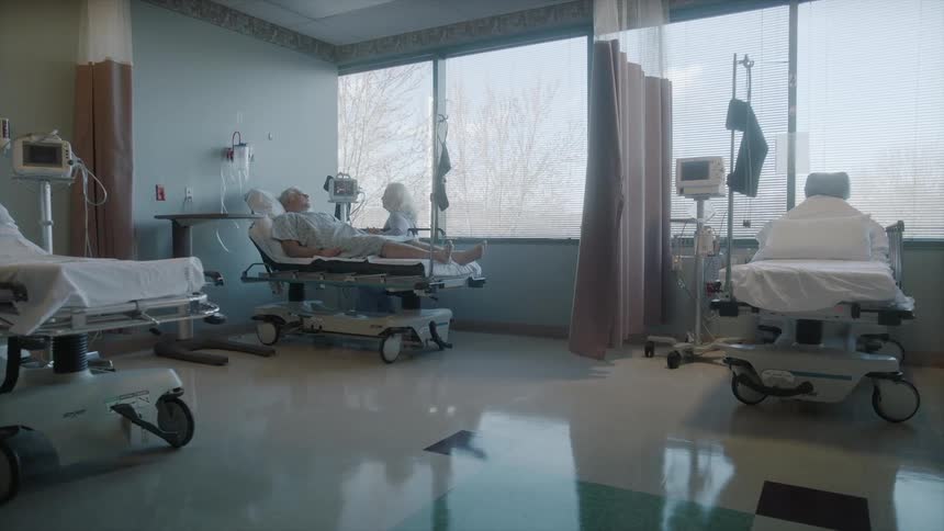 Hospital room with a man lying in bed in front of a large window