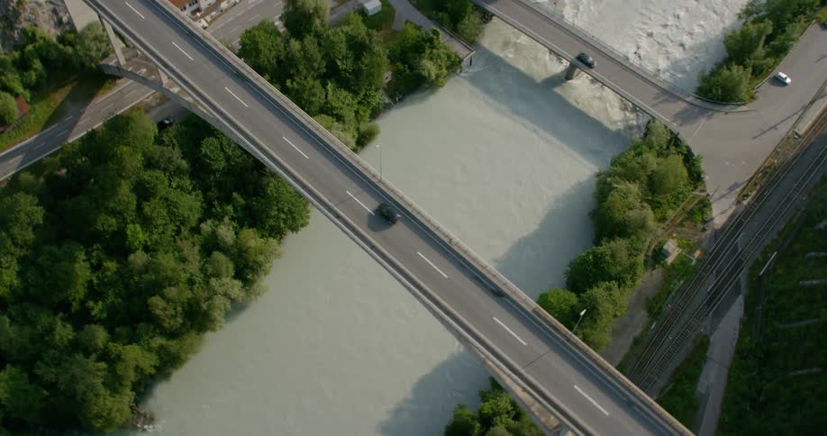 The cars travel on the roads and bridge near the river