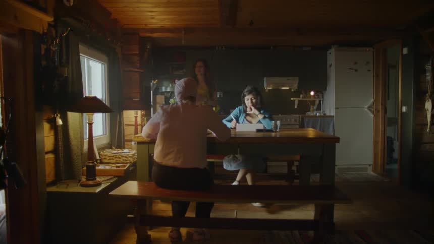 The woman walks past two sitting at the dining room table